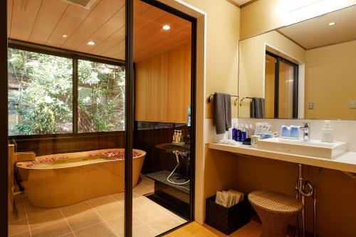 a bathroom with a tub and a sink at Yuraku Kinosaki Spa & Gardens in Toyooka