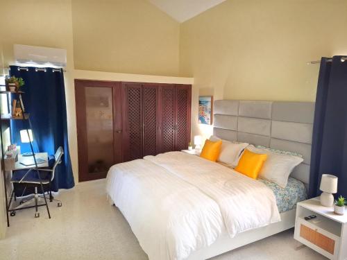 Un dormitorio con una gran cama blanca con almohadas naranjas. en Paramount Views, en San Felipe de Puerto Plata