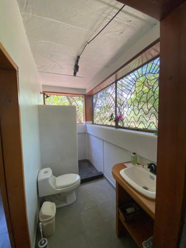 een badkamer met toilet, wastafel en raam bij Casa Mariposa Ometepe Suite in Santa Cruz