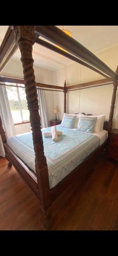 a canopy bed with a wooden frame in a bedroom at Miramar Cottage in Denmark