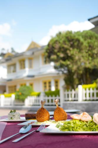 a table with plates of food on a purple table cloth at Eastend Munnar in Munnar