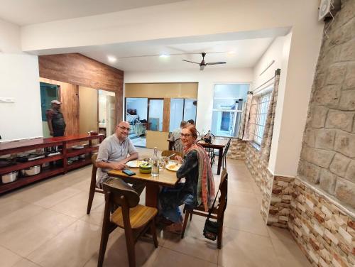 two people sitting at a table in a dining room at Hornbill Castle in Vālpārai