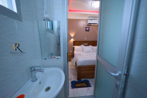 a bathroom with a sink and a bedroom with a bed at Résidence Vinelly in Douala