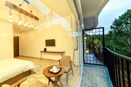a bedroom with a bed and a table on a balcony at Romeo & Juliet Dalat in Da Lat