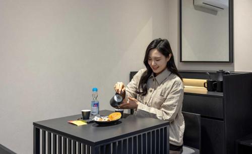 a woman standing in front of a table with a bowl of food at Aank Ryokan Hotel Jeonju in Jeonju