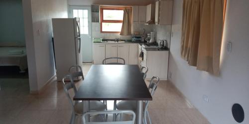 a kitchen with a table and chairs and a refrigerator at Cabañas Kaldak in Lago Puelo