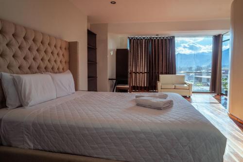 a bedroom with a large bed with a large window at Hotel California Urubamba in Urubamba