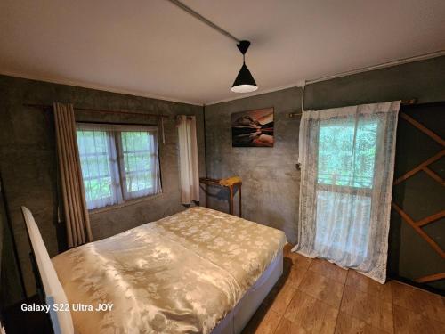 a bedroom with a bed and two windows at สวนบนคอทเทจ เชียงดาว in Ban Tham