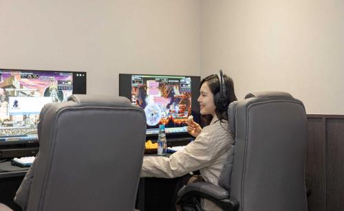 a woman wearing headphones playing a video game at Aank Ryokan Hotel Jeonju in Jeonju