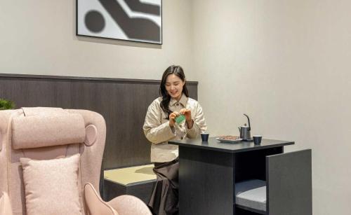 a woman sitting at a table eating food at Aank Ryokan Hotel Jeonju in Jeonju