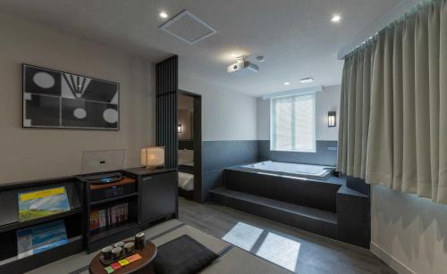 a living room with a tub and a television at Aank Ryokan Hotel Jeonju in Jeonju