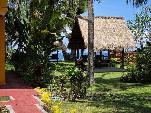 a resort with a thatch roof and the ocean at Sunsethouse Lombok in Senggigi 