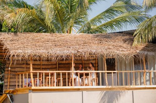 a group of people sitting on the balcony of a straw hut at Chamee Oasis Villa in Ranna