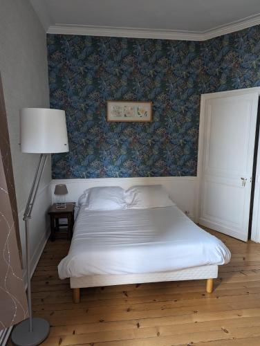 a bedroom with a white bed and a blue wall at Le Manoir de Conteville in Paluel