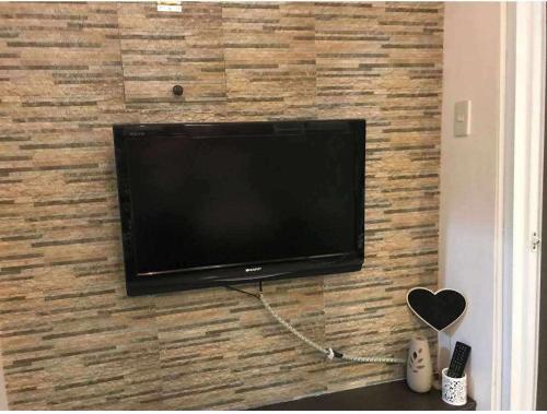 Ein Flachbildfernseher hängt an einer Backsteinwand. in der Unterkunft Tagaytay Cityland Taal Lake View with balcony by SAB in Tagaytay
