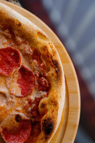a slice of pepperoni pizza on a wooden plate at Bishkek Centrum Hotel in Bishkek