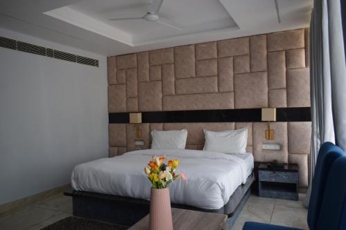 a bedroom with a bed and a vase of flowers at Country Ambience Hotel in Haldwāni