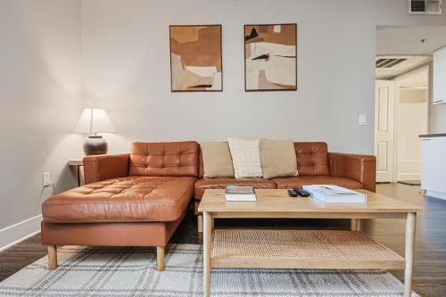 a living room with a brown leather couch and a table at Sunny 2BDR in SM Pool & Gym - 5 min to the beach! in Los Angeles