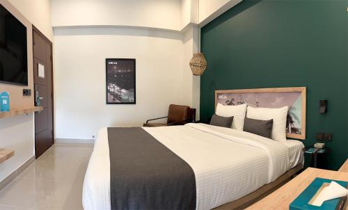 a bedroom with a large bed and a green wall at LOKAL Flagship x Karachi - DHA in Karachi