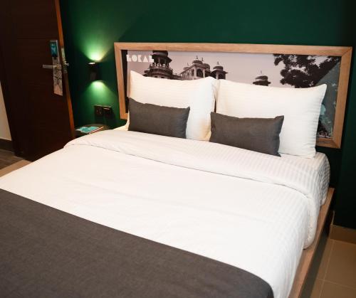 a large bed with white sheets and pillows at LOKAL Flagship x Karachi - DHA in Karachi