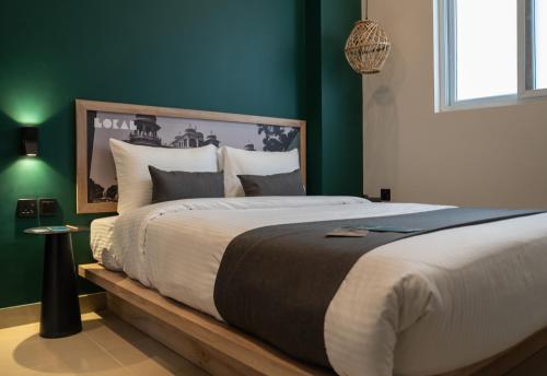 a large bed in a bedroom with green walls at LOKAL Flagship x Karachi - DHA in Karachi