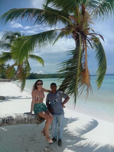 a man and woman sitting on a palm tree on a beach at Amaro Homestay in Nuhu Tawun