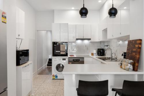 a kitchen with white cabinets and a washer and dryer at Lume Outlook - Dedicated Workspace, Wi-FI, Parking in Unley