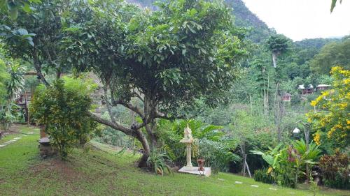 a small shrine under a tree in a field at สวนบนคอทเทจ เชียงดาว in Ban Tham