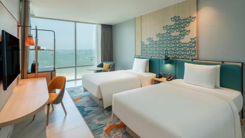 a hotel room with two beds and a desk at Holiday Inn Pattaya by IHG in Pattaya Central