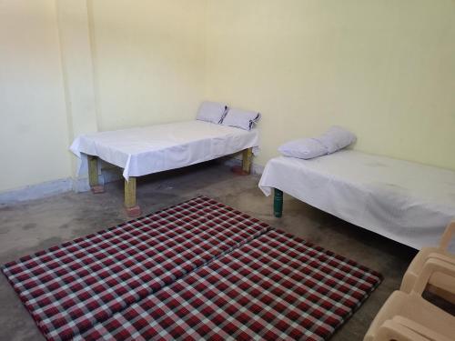 a room with two beds and a rug in it at Samriddhi Home stay in Prayagraj