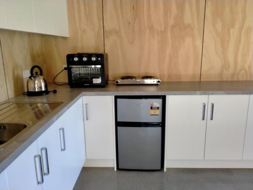 a kitchen with white cabinets and a black refrigerator at TheShed in Hira