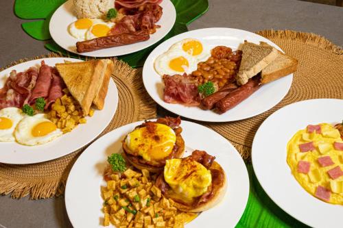 a table with plates of breakfast food on it at SureStay Plus Hotel by Best Western AC LUXE Angeles City in Angeles