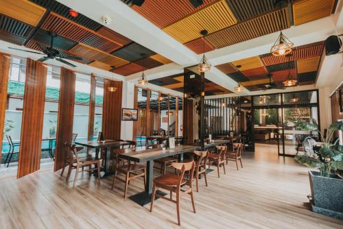 a restaurant with wooden tables and chairs and windows at SureStay Plus Hotel by Best Western AC LUXE Angeles City in Angeles