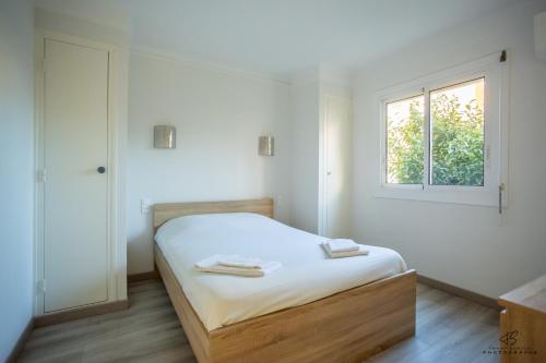 une chambre blanche avec un lit et une fenêtre dans l'établissement Le coin des agrumes Jardin Proche Centre Ville, à Perpignan