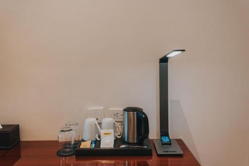 a table with a coffee maker and a lamp on it at SureStay Plus Hotel by Best Western AC LUXE Angeles City in Angeles