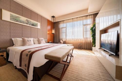 a bedroom with a large bed and a flat screen tv at Chengdu Joyhub Air Hotel in Chengdu