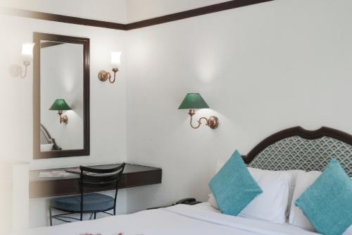 a bedroom with a bed and a mirror and a chair at Eastend Munnar in Munnar