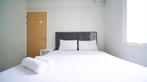 a bedroom with a bed with towels on it at Best Location and Comfy 2BR at Bale Hinggil Apartment By Travelio in Medokanayu