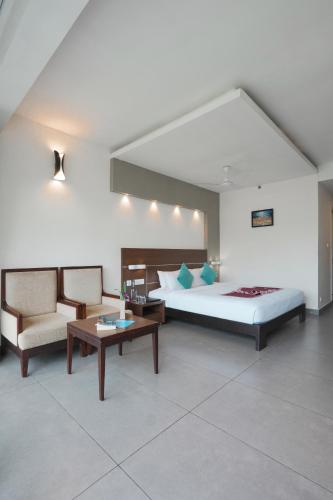 a bedroom with a bed and a couch and a table at Eastend Munnar in Munnar