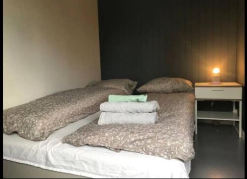 a room with a bed with pillows and a table with a candle at Cozy apt by subway, parking in Lijordet