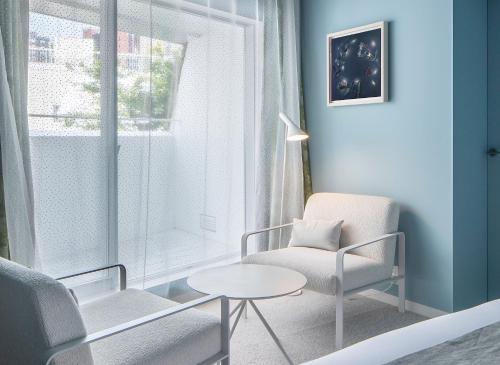 a living room with a chair and a table and a window at SHIROIYA HOTEL in Maebashi