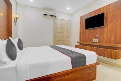 a bedroom with a white bed and a flat screen tv at Super Townhouse Rcc Pride in Hyderabad