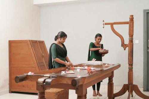 two women standing in front of a wooden table at Eastend Munnar in Munnar