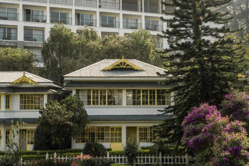 a large house with a building in the background at Eastend Munnar in Munnar