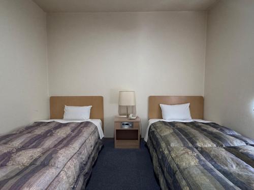 two beds in a hotel room with two beds sidx sidx sidx at Business Hotel Okadaya Toyohashi in Toyohashi
