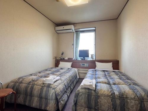 a hotel room with two beds and a window at Business Hotel Okadaya Toyohashi in Toyohashi
