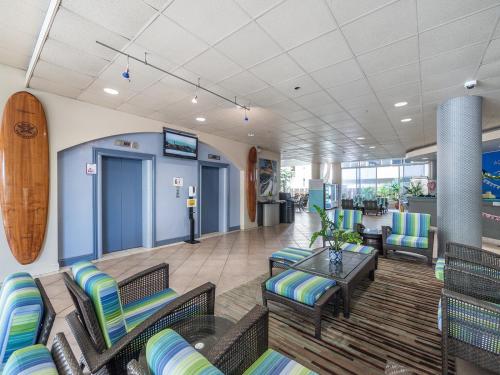 a lobby with chairs and tables and a surfboard on the wall at Aqua Aloha Surf Waikiki Hotel, 5 minute walk to the beach in Honolulu
