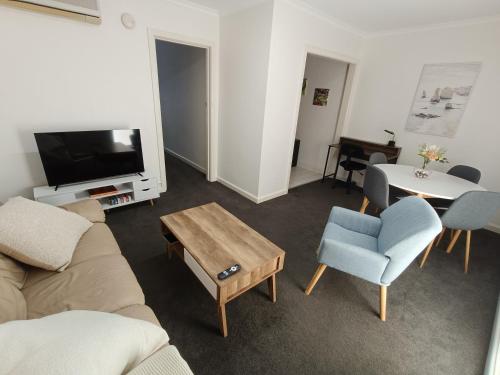 a living room with a couch and a table and a tv at Cute, Cosy and Central Apartment 1 in Essendon with Free Parking in Melbourne