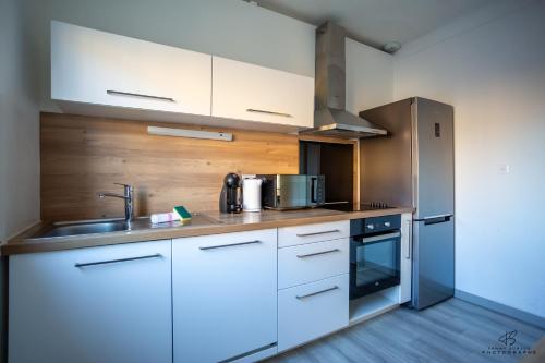 une cuisine avec des armoires blanches et des appareils en acier inoxydable dans l'établissement L'oranger Proche centre ville WIFINETFLIX, à Perpignan