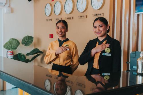 two people standing in a room with clocks on the wall at SureStay Studio by Best Western Clarkview Angeles City in Angeles